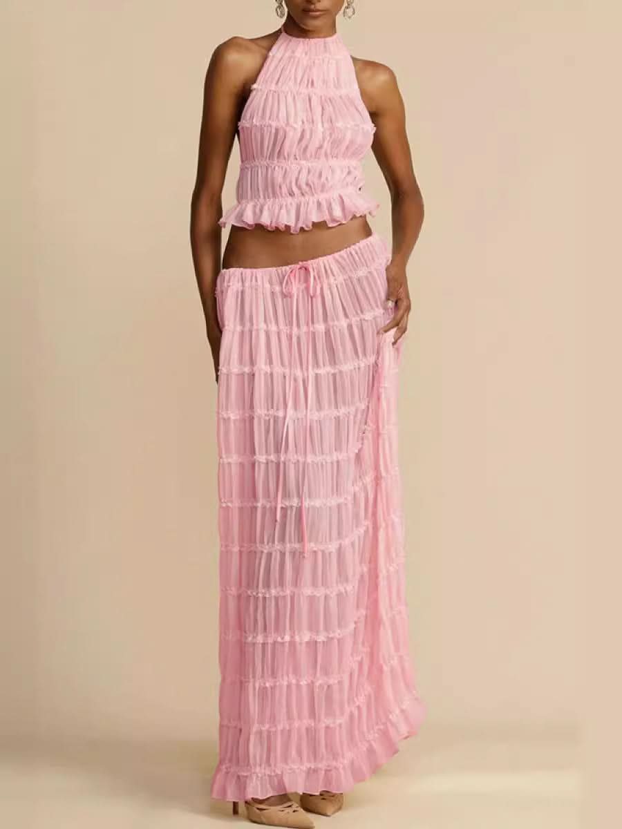 Woman wearing Isla Breeze Two-Piece Set with high-neck crop top and flowy maxi skirt in pink textured crinkle fabric ideal for summer.