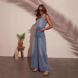 Woman wearing Denim Dream Jumpsuit with V-neck, buttons, and wide-leg style in light-wash denim, styled with boots.
