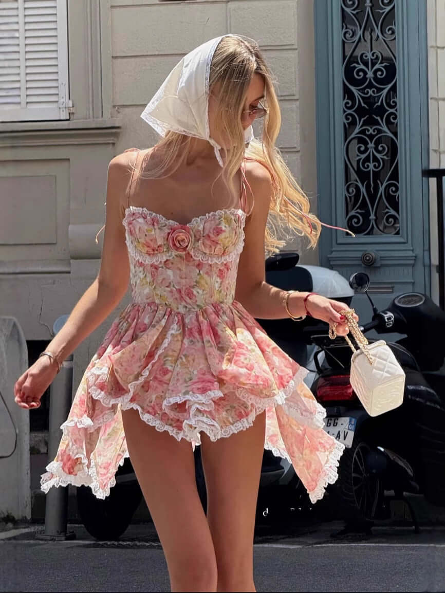Woman in Parisian Bloom Dress with floral design, bustier top, lace trims, styled with headscarf, standing on street.