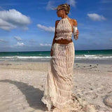 Woman wearing Isla Breeze Two-Piece Set on beach, featuring crinkle crop top and flowy maxi skirt, ideal for summer and resort getaways.